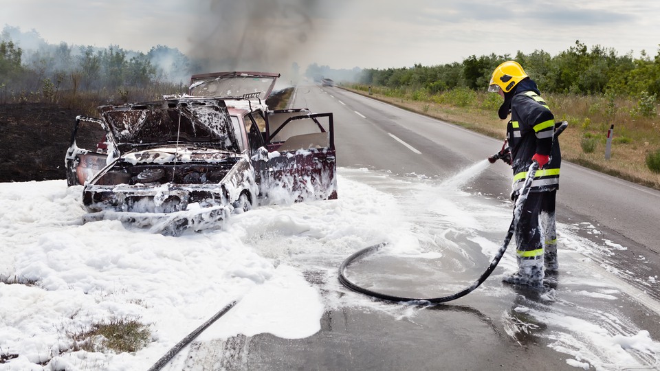 En brandsoldat släcker en bilbrand med brandskum. 